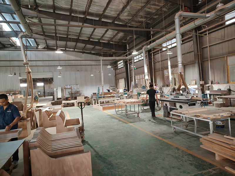View of Hyman Hospitality manufacturing floor showing woodworking operations, raw materials, and CNC machinery for custom furniture production.