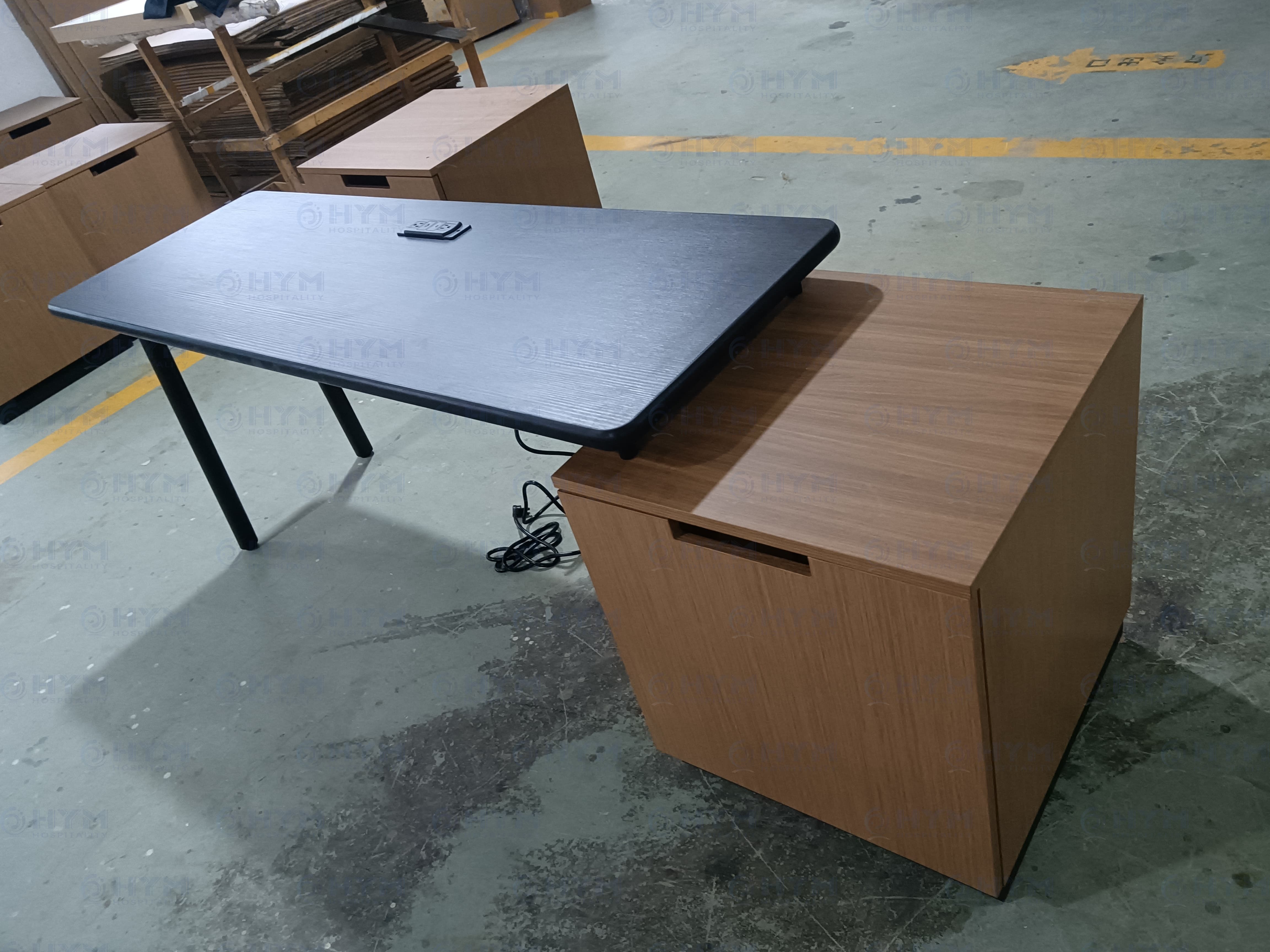 Marriott brand-compliant Fairfield Inn & Suites guestroom desk and storage console featuring a black textured surface with integrated UL-listed power outlet and a matching natural wood-grain storage pedestal.