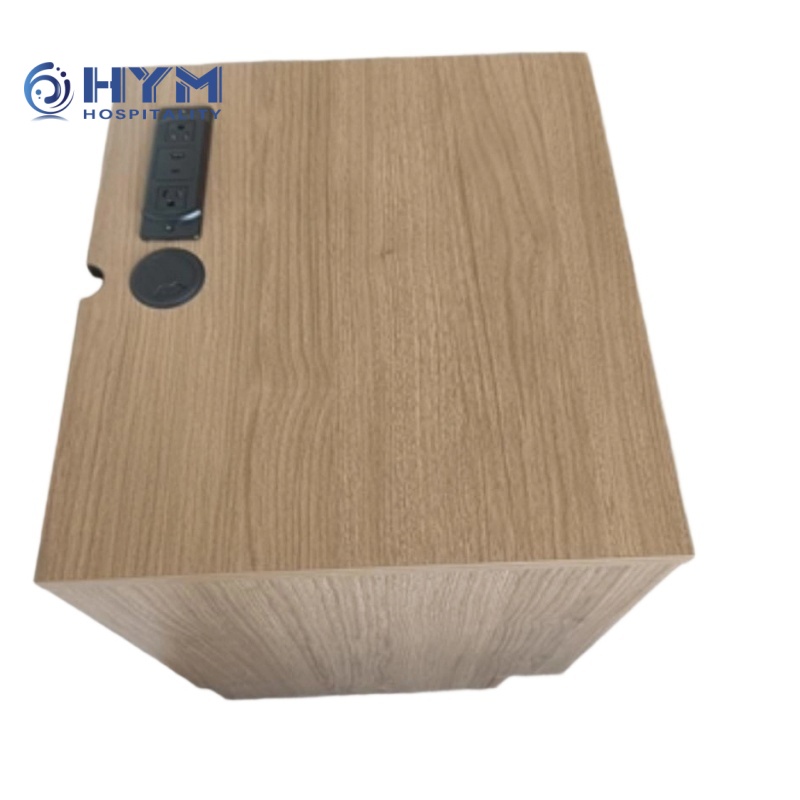 Hampton by Hilton brand-standard nightstand featuring an integrated power hub with dual AC and USB ports, paired with a 2-inch black cable management grommet.