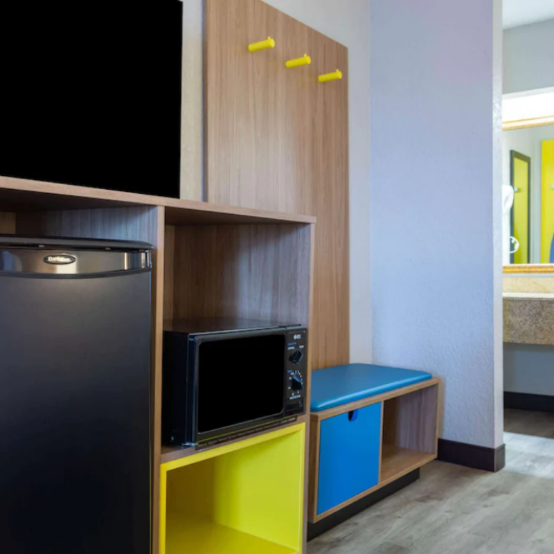Integrated guestroom hub for Days Inn featuring the GR-301 closet panel with yellow hooks and the GR-305 bench with blue upholstery, aligned with the Wyndham Dawn prototype.