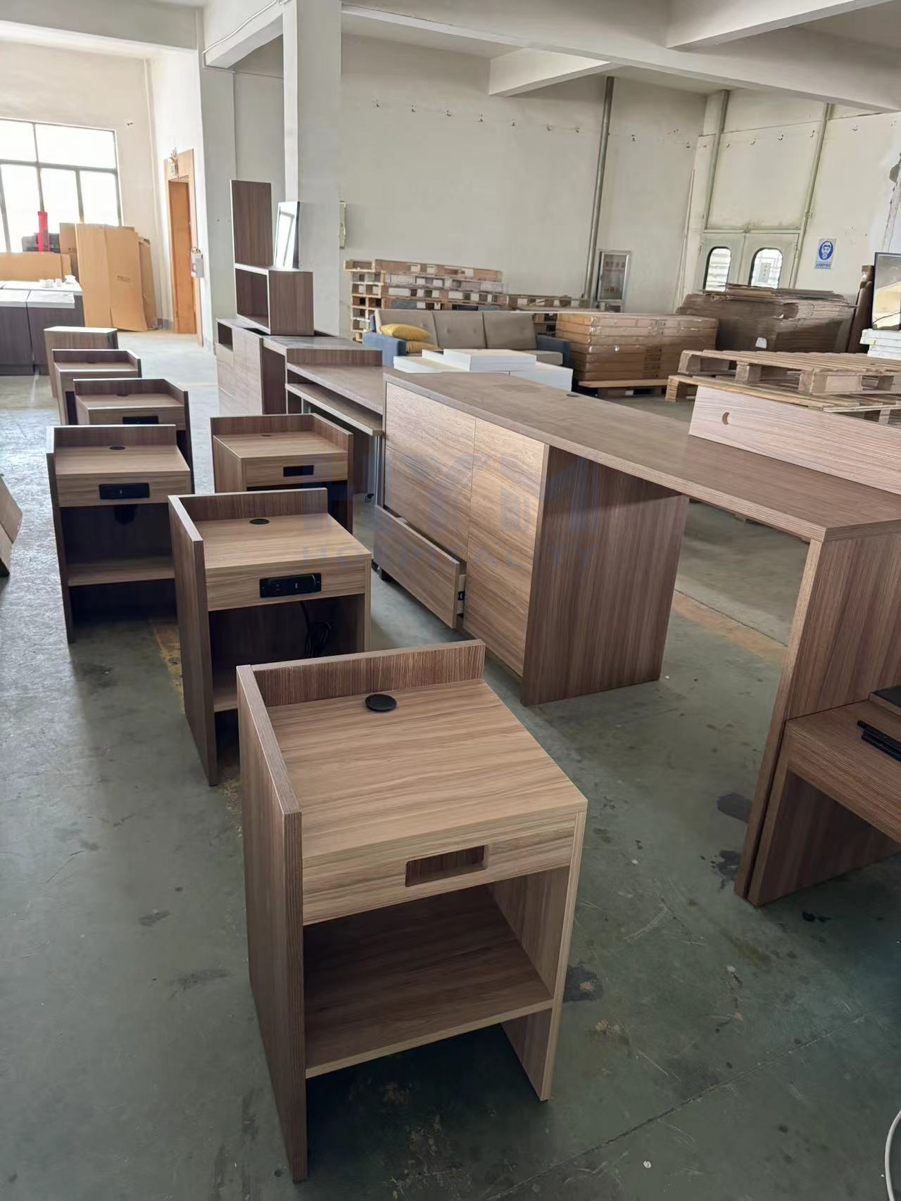 Factory workshop showing mass production of Home2 by Hilton furniture sets, including GR-323 nightstands and matching guest room desks.