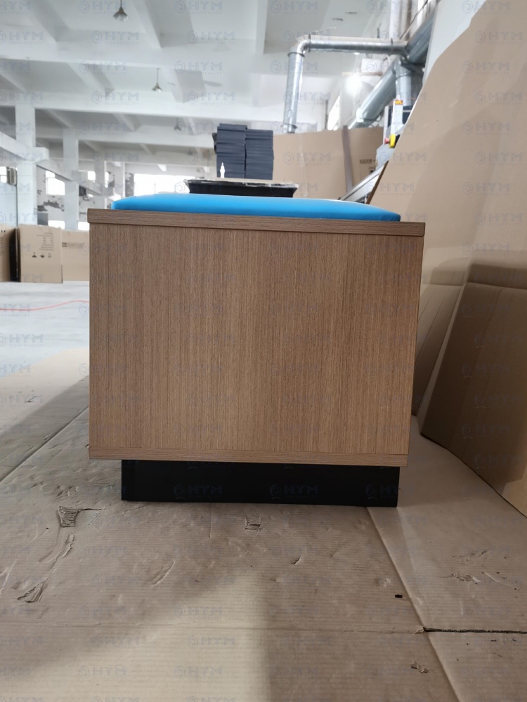 Side perspective of the Days Inn by Wyndham Dawn scheme luggage bench GR-305B-CG, showing the high-pressure laminate wood grain finish and moisture-resistant recessed black base.