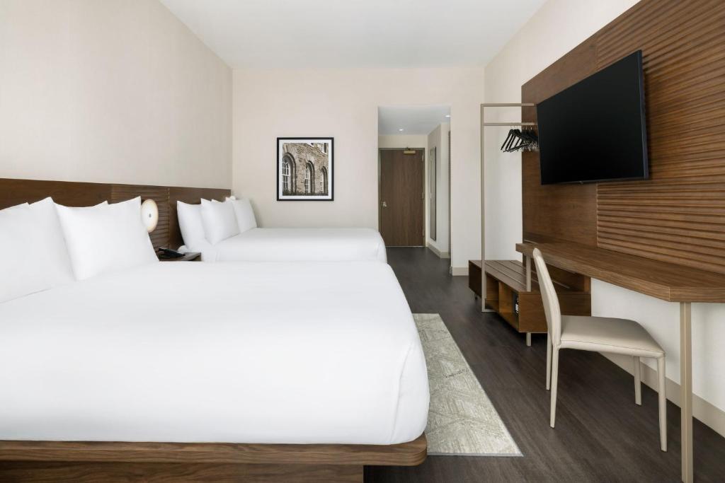 Sleek wall-mounted desk and integrated TV console for AC Hotels Double Queen suites, utilizing high-pressure laminate (HPL) for high-traffic durability.