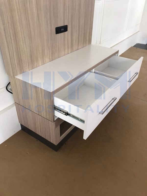 Detail shot of hotel TV cabinet with open drawer showing ball-bearing slides and white interior finish