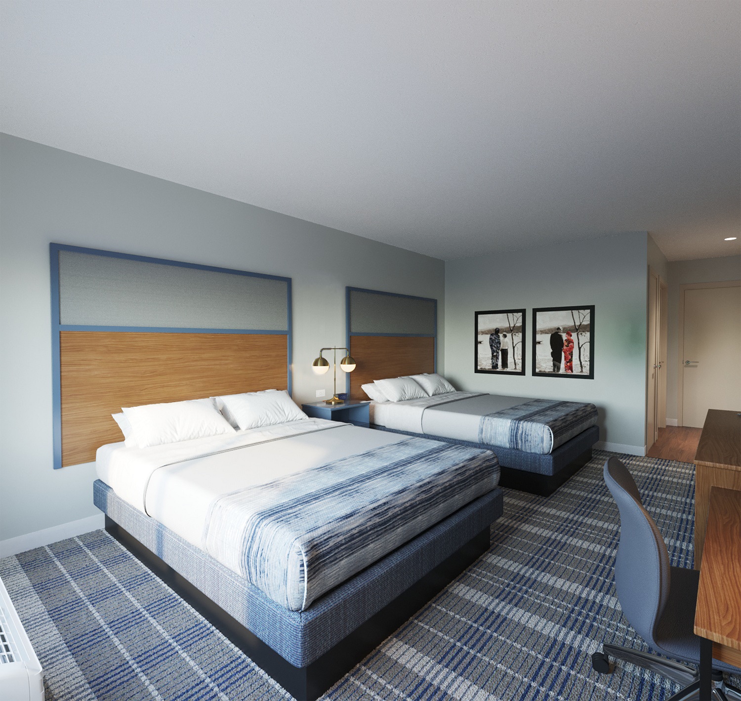 AmericInn Hotel & Suites Double Queen guestroom scene showing two beds with coordinated wood grain headboards, desk area, and hospitality grade carpet.