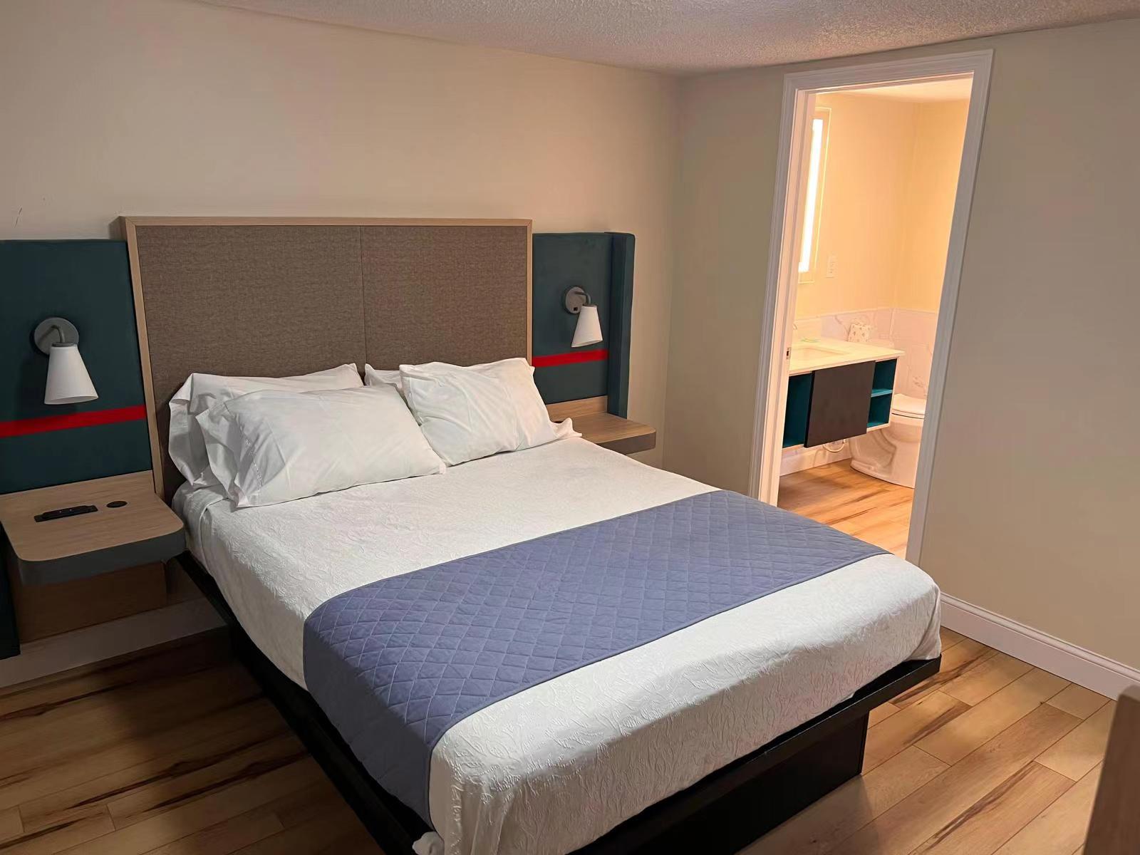 Audit-ready Avid Hotels guestroom headboard with integrated sconce lighting and ADA compliant nightstand elevation.