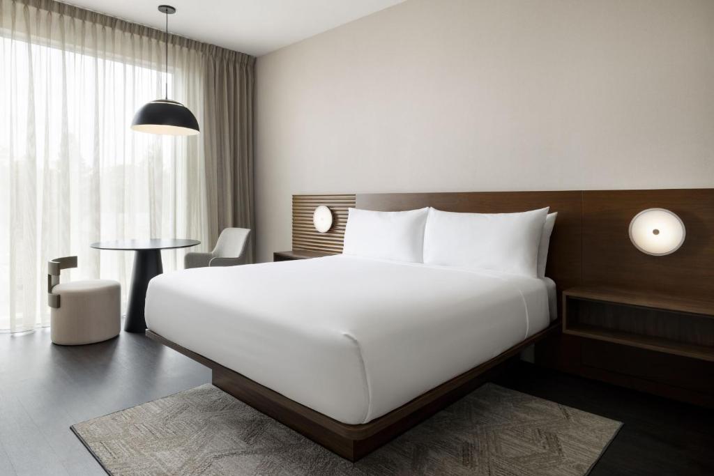 Marriott brand-compliant King guestroom FF&E for AC Hotels featuring an integrated walnut headboard with circular architectural sconces.