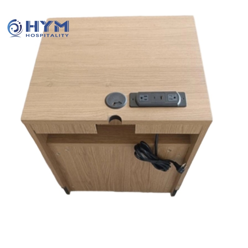 Top-down view of a Hilton guestroom nightstand in Wilsonart Sap Walnut finish, showing a factory-installed SELF Electronics power strip and rear cable routing for onsite installation.