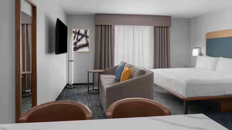 Application view of Homewood Suites GR-323 furniture in a one-bedroom king suite, showing the defined living area with sofa and coffee table.