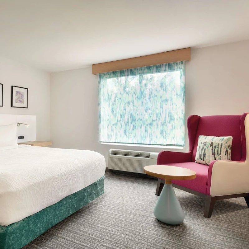 Turnkey guestroom FF&E solution for Hilton Garden Inn Project Modern, showcasing the GR-101 lounge chair, upholstered bed base, and coordinating lighting.