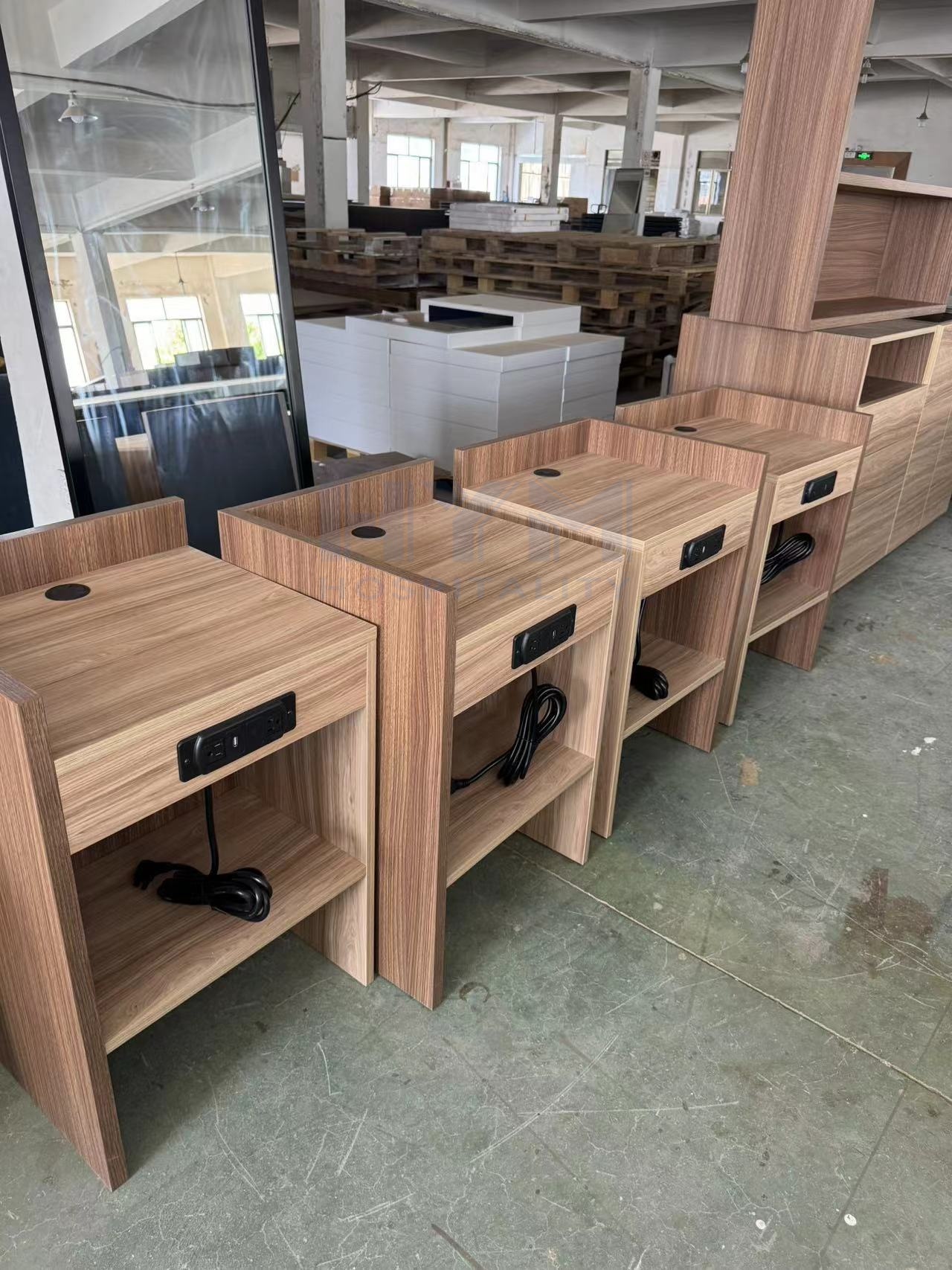 In-production row of GR-323 hotel nightstands with built-in power outlets, showcasing consistent quality for high-volume hospitality orders.
