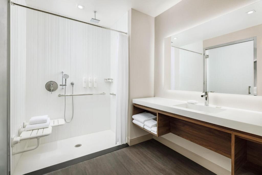 ADA compliant floating bathroom vanity for AC Hotels by Marriott, featuring required knee clearance, quartz top, and integrated towel shelving.