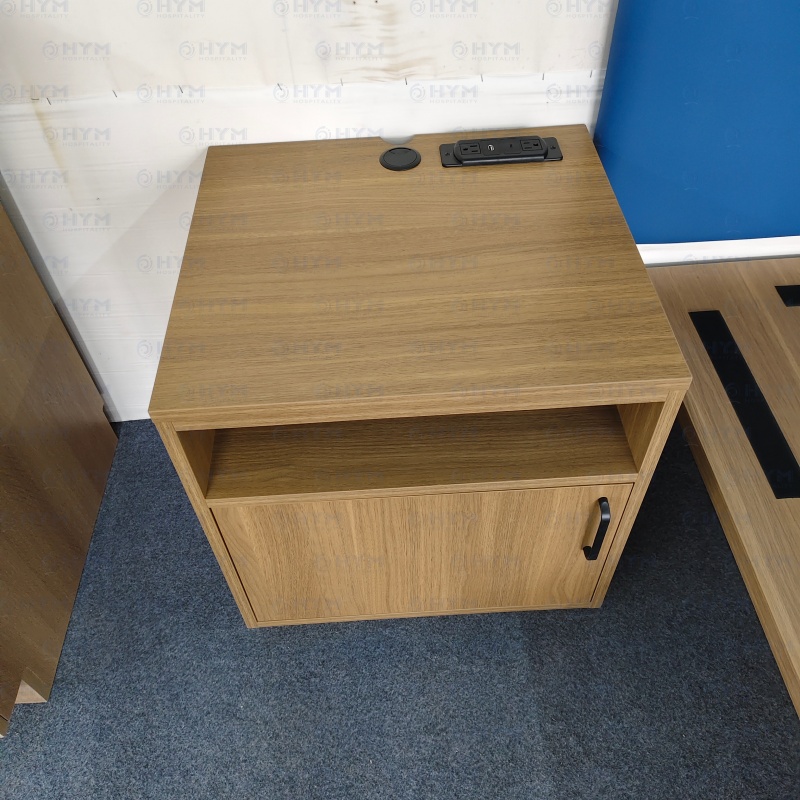 Top view of Hilton brand standard nightstand showing integrated power strip cutout and cable management grommet in Sap Walnut finish.