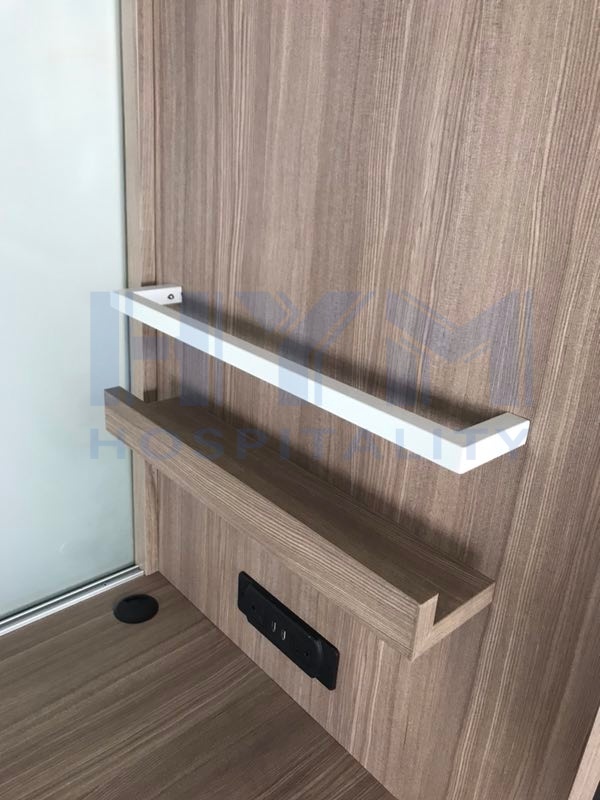 SpringHill Suites integrated desk detail featuring storage shelf with white guardrail and recessed power strip