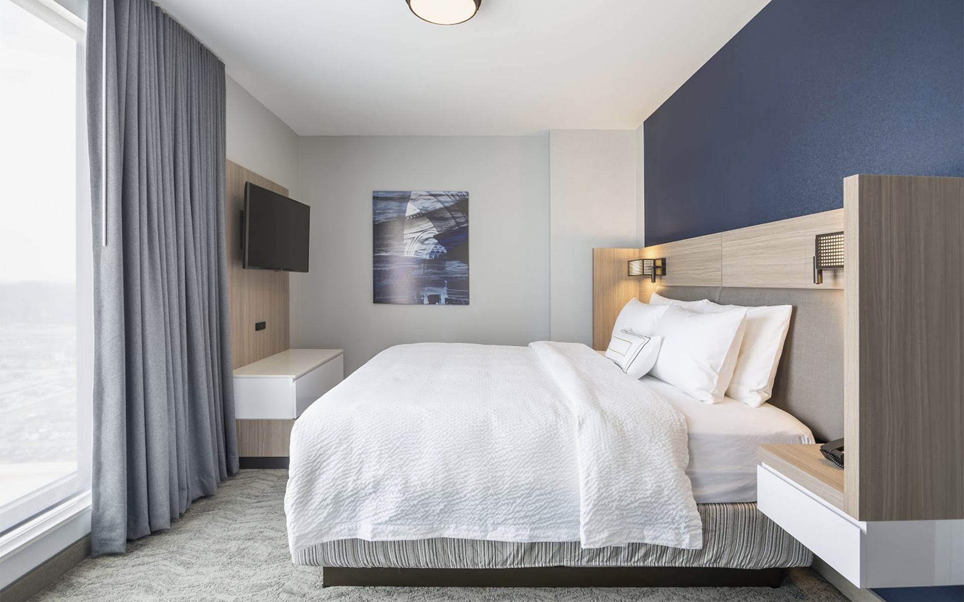 SpringHill Suites King guestroom configuration featuring integrated headboard, nightstands, and TV cabinet for hotel renovation.