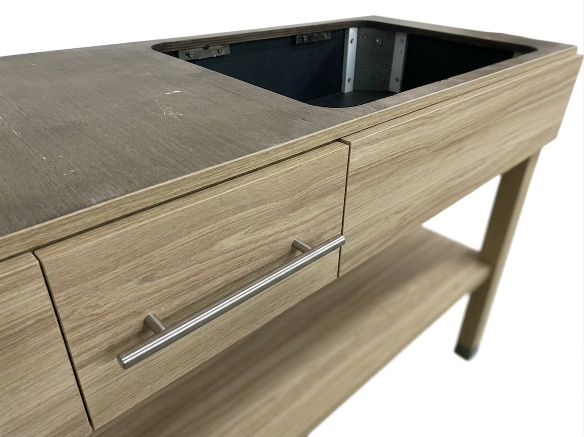 Close-up of commercial-grade brushed nickel drawer pulls and textured wood-grain HPL finish on a hotel vanity cabinet.